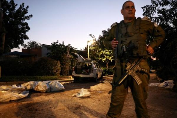 An Israeli military officer stands in front of dead bodies as they lay on the ground following a mass infiltration by Hamas gunmen from the Gaza Strip, in Kibbutz Beeri in southern Israel, October 11, 2023. REUTERS/Violeta Santos Moura