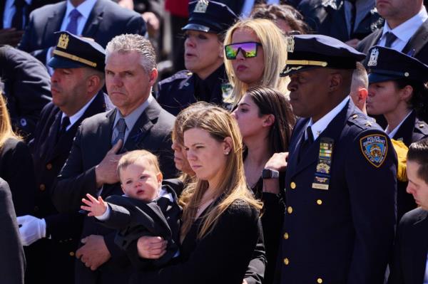 Stephanie Diller, the wife of slain NYPD officer Jo<em></em>nathan Diller, holds her son, Ryan, 1, as he reaches towards the casket of his father.