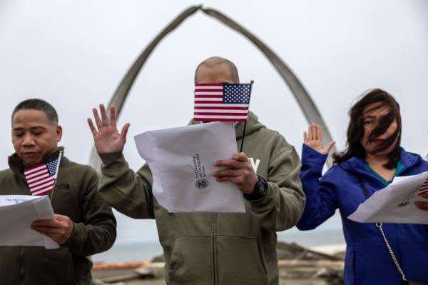 Immigrants take the oath of allegiance to the United States during a naturalization ceremony held in front of the 