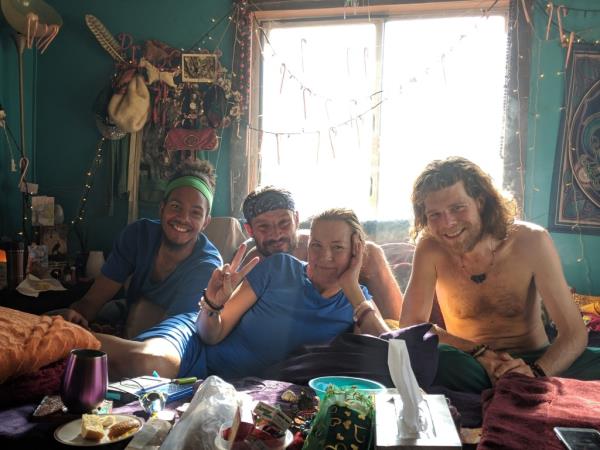 Amy Carlson sitting on a couch with hippie-looking men. 