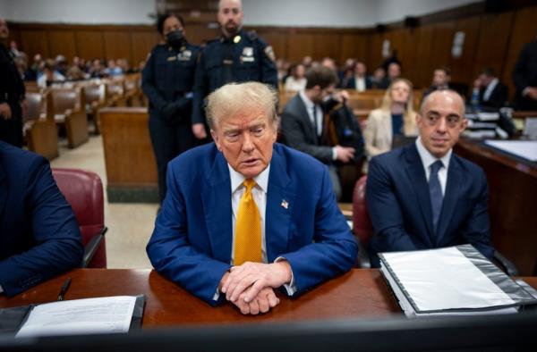 Former US President Do<em></em>nald Trump at his trial in Manhattan Criminal Court, seated at a desk with people in the background