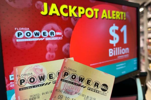 Powerball tickets are shown in front of a screen displaying the estimated jackpot