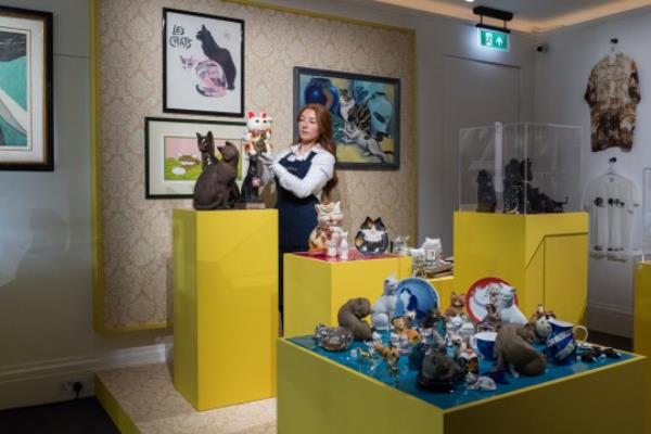 LONDON, UNITED KINGDOM - AUGUST 03: An art handler poses with a collection of feline ornaments in in a whimsical variety of decorative styles during a photocall at Sotheby's auction house for the unveiling of Freddie Mercury's entire private collection ahead of an exhibition and six dedicated sales in London, United Kingdom on August 03, 2023. 'Freddie Mercury: A World of His Own' exhibition starring stage costumes, handwritten lyrics, fine and decorative arts, Japanese art, precious objects and a trove of perso<em></em>nal belo<em></em>ngings will be open to the public between August 4th and September 5th, before the items are offered across six dedicated auctions, each one devoted to a different aspect of Mercurys life, both public and private. (Photo by Wiktor Szymanowicz/Anadolu Agency via Getty Images)