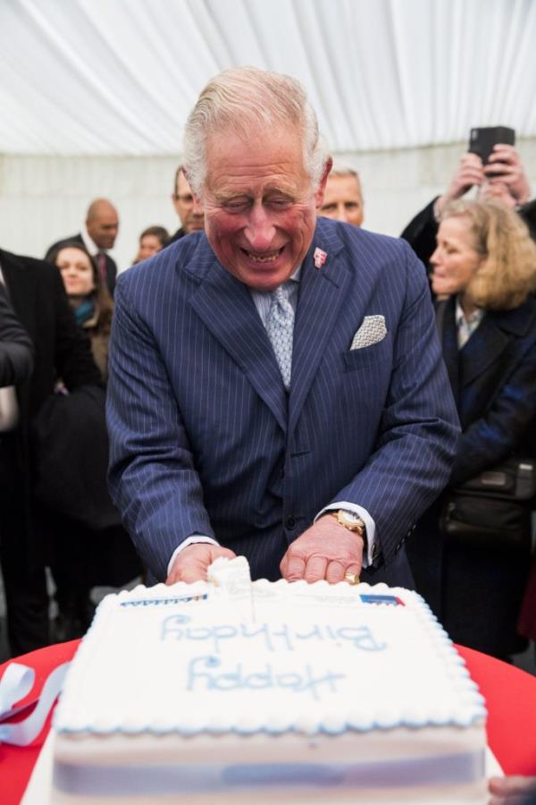 Prince Charles cutting a birthday cake at the Waste-To-Wealth Summit in London, surrounded by leaders from business, government, and academia.