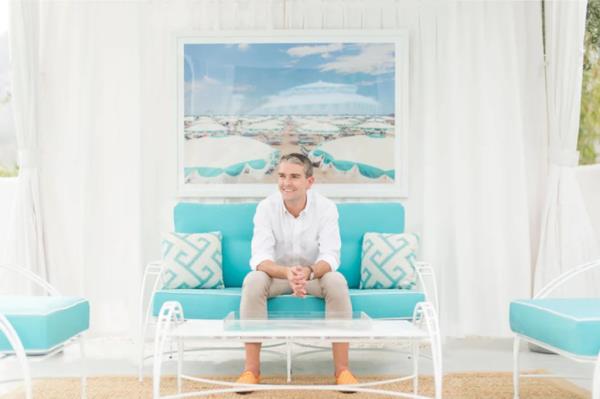 Photographer Gray Malin sitting on a blue couch