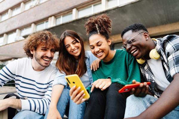 Group of university students sitting together and sharing co<em></em>ntent on mobile phones