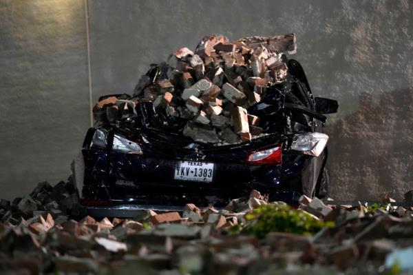 A car crushed by falling bricks from a fallen building wall sits in a downtown parking lot after a severe thunderstorm passed through, Thursday, May 16, 2024.