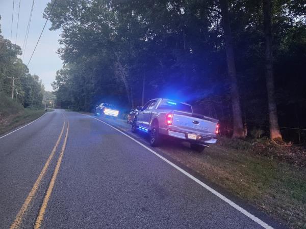 A police cruiser on the side of a country road.