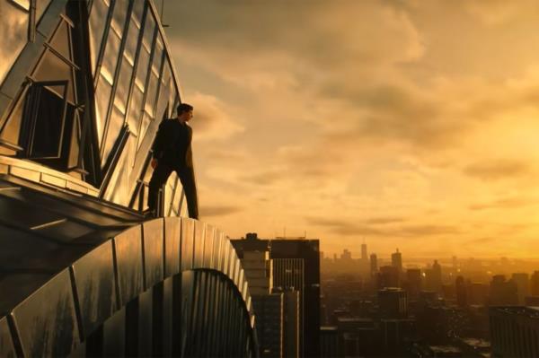 Adam Driver on a ledge looking at a cityscape. 