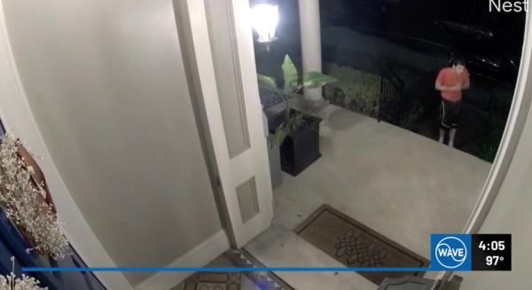 Doorbell camera footage showing a man in a red shirt walking up the stairs to a suburban home's front porch.