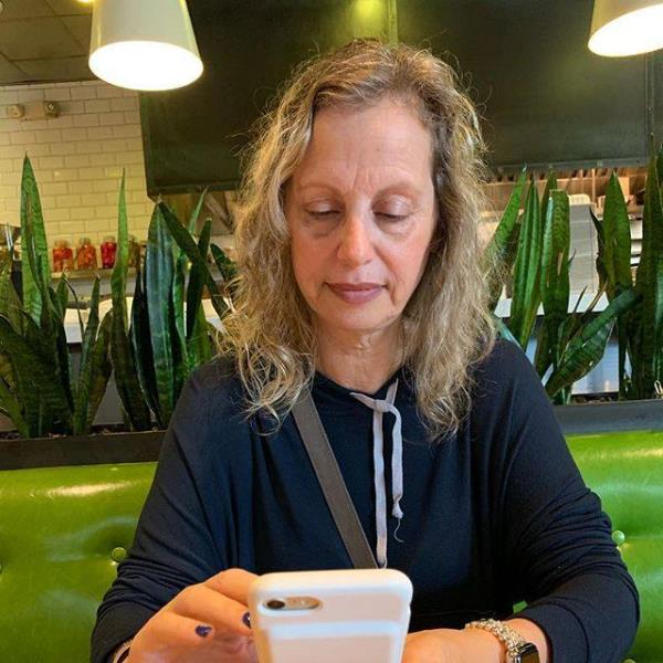 Howie Mandel's wife, Terry Mandel, sitting at a table looking at a cell phone