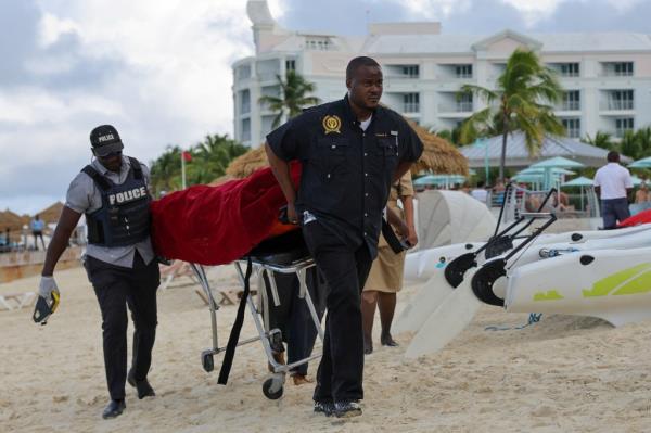 Police carry body covered in red bag off the beach on a stretcher 