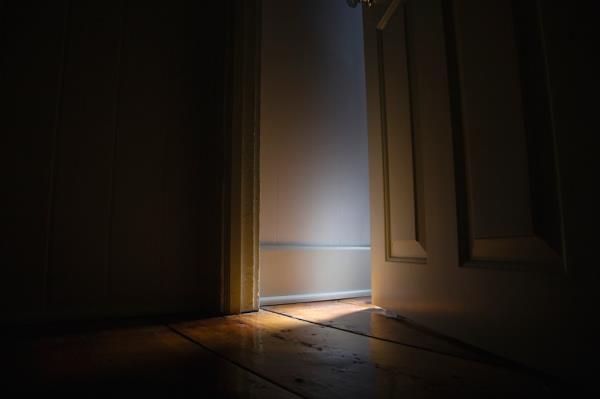 Worried Woman Watching Outside from a Wooden Window Shutter