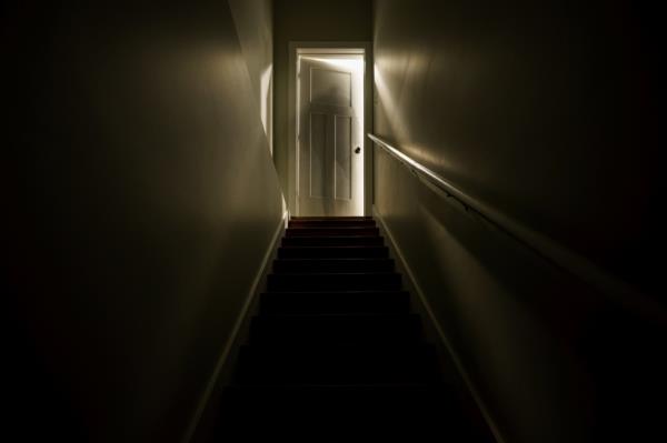 A dark stairwell illuminated by a slightly opened door