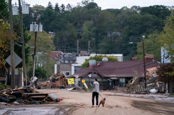 Mary Grace and her dog, Marley, walk around the Biltmore Village in the aftermath of Hurricane Helene on September 29, 2024 in Asheville, North Carolina. 