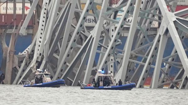 Police boats surrounding a cargo ship stuck under the Francis Scott Key Bridge in Baltimore, Maryland after a collision