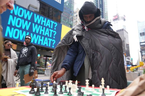 Nigerian chess master Tunde o<em></em>nakoya wrapped in a blanket, playing chess during his marathon challenge in Times Square