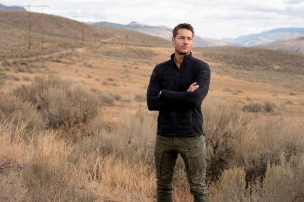 Justin Hartley looking moody in a field. 