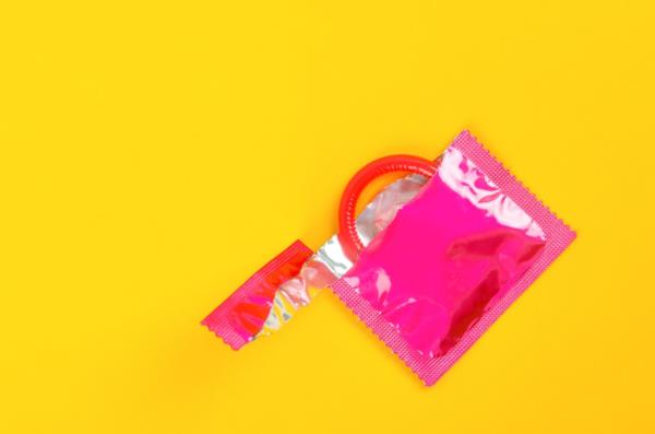 Pink opened co<em></em>ndom unpack on a yellow background. 