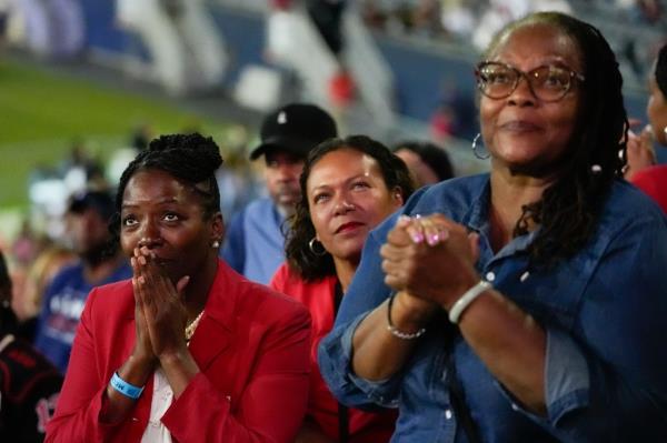 People watching Vice President Kamala Harris speak on a big screen at a watch party in Soldier Field for the Democratic Natio<em></em>nal Convention, 2024.