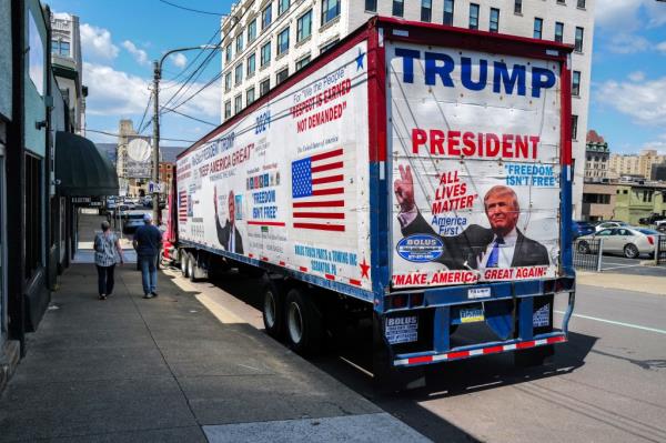 Pedestrians walk past a trailer-truck promoting former US President Do<em></em>nald Trump parked on a street in Scranton, Pennsylvania on April 15, 2024