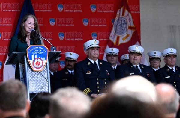 FDNY Commissio<em></em>ner Laura Kavanaugh speaks at a podium with the fdny symbol on it as chiefs in formal dress uniform stand nearby