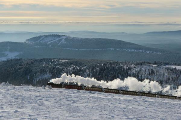 A steam train of the Harzer Schmalspurbahn narrow-gauge railway makes its way through the snowy landscape to reach the summit of the Brocken mountain in Schierke in the Harz region