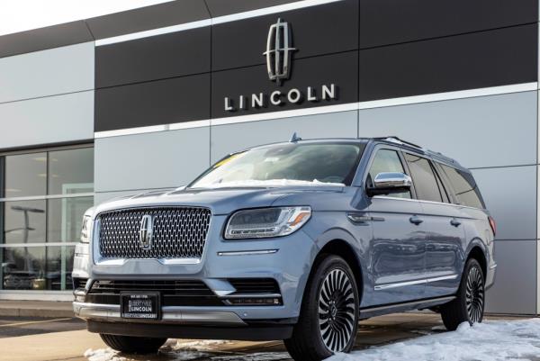 A Lincoln Navigator parked at a Ford dealership with buildings in the background.
