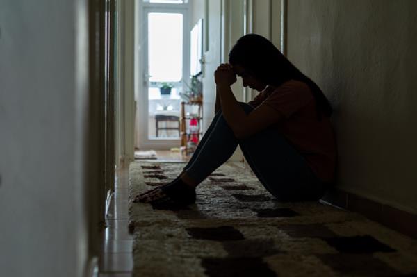 Sad woman sitting corridor floor