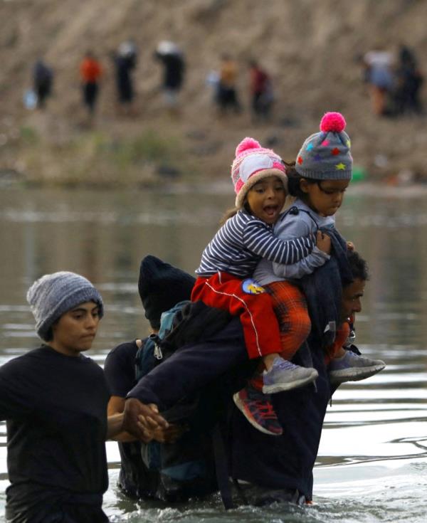 Venezuelan migrant Juan carries his two daughters while crossing the Rio Bravo river.