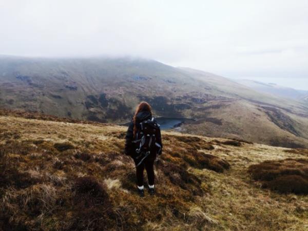 Lowri standing on a hill, looking out to a beautiful nature landscape