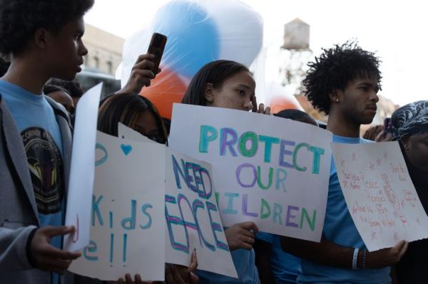 Carly Britt 16, ctr. and other young activists hold posters at a baloon  release in memory of Jahmeik Modlin  in front of his apartment building