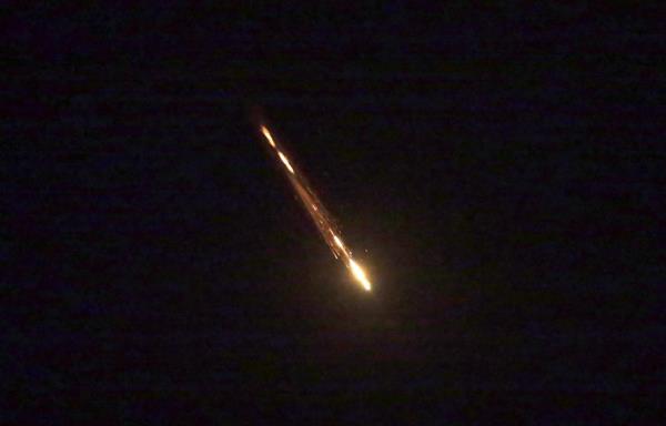 A flashing missile breaks up against a black sky.
