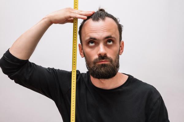 Man measuring his height with measuring stick. 