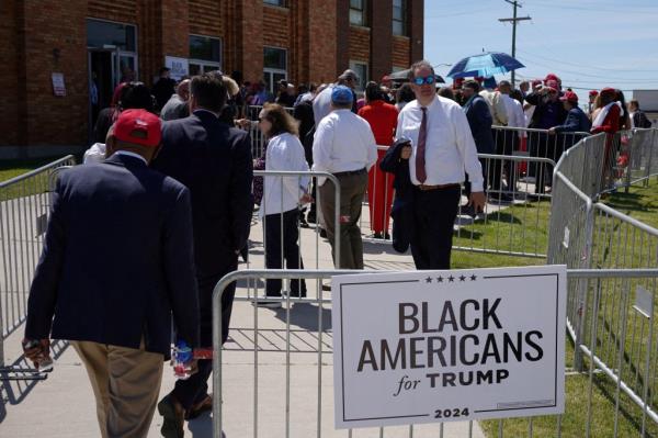 Audience members lined up behind 'Black Americans for Trump' sign at a campaign roundtable in Detroit, Michigan