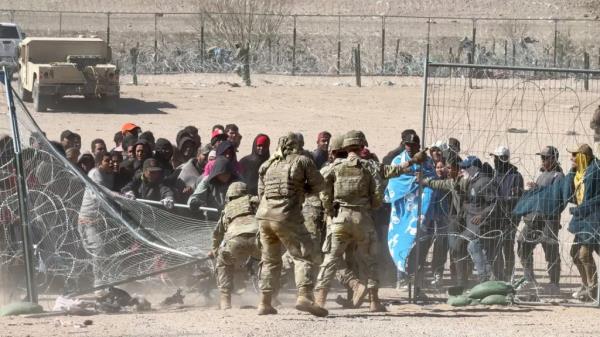 Migrants force their way across the border.