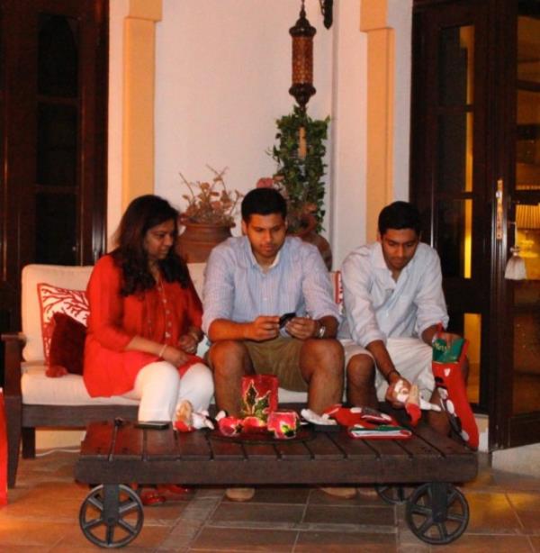 Vidhu with Rudy and Arjun at Christmas. They're sitting on a low sofa, filling stockings with small presents.