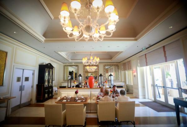 A group of people sitting at a table in Temple Orange Mediterranean Bistro at Eau Palm Beach Resort, Florida on May 14, 2017.