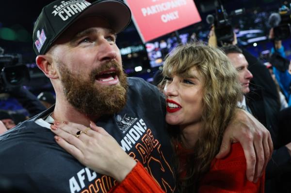 Travis Kelce smiling with his arm around Taylor Swift. 