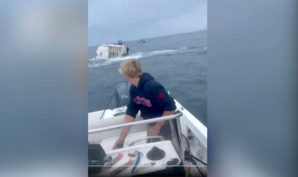 Breaching humpback whale topples boat off.