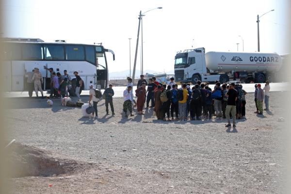 Afghan refugees disembarking from an Iranian bus at a registration center near the Afghanistan-Iran border after deportation from Iran