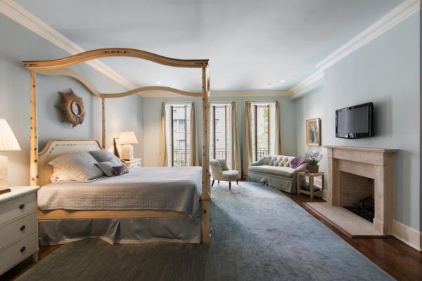 Spacious bedroom with a four poster bed and a fireplace at 160 East 83rd Street