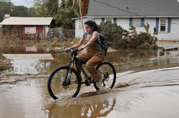 A woman in Swannanoa, NC, bicycles through floodwaters.