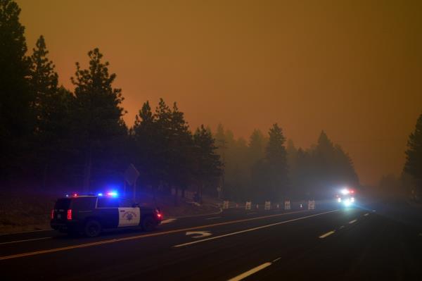 Police vehicles are seen near a road closure as smoke from the Line Fire fills the air Saturday, Sept. 7, 2024, in Running Springs, Calif. 