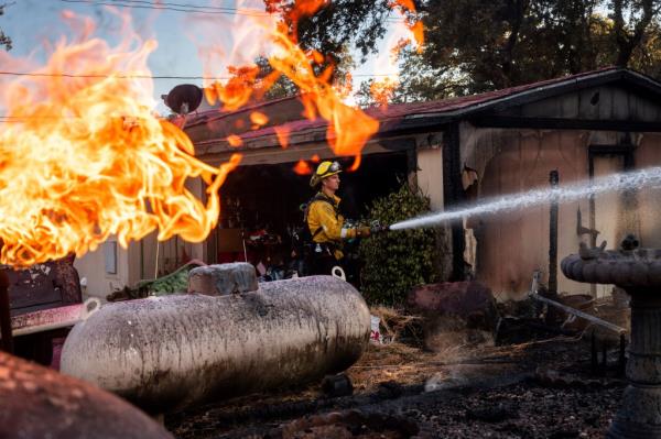 Firefighter Nolan Graham sprays water around a scorched garage as the Boyles fire burns in Clearlake, Calif., on Sunday, Sept. 8, 2024. 