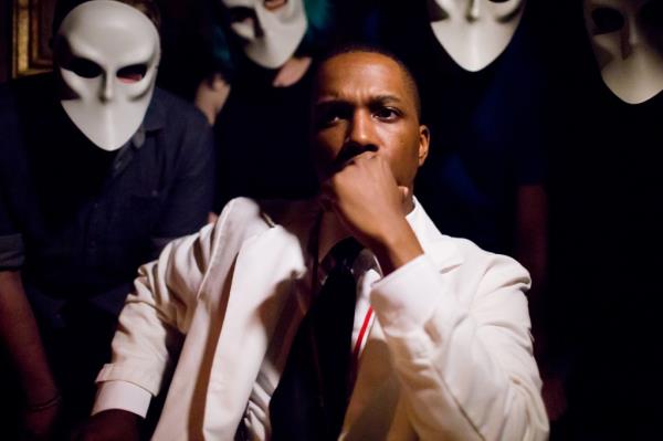 Leslie Odom Jr. wears a white suit and looks straight at the camera in 