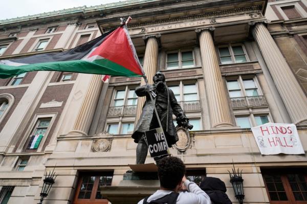 A student protester parades a Palestinian flag outside the entrance to Hamilton Hall.
