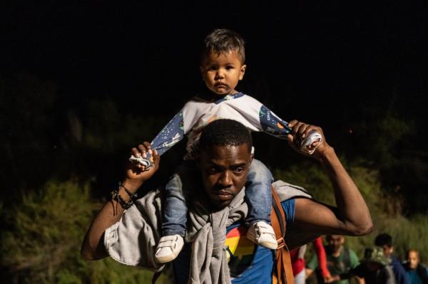 A migrant walking with his child to turn himself into US Border Patrol after crossing the border near Yuma.