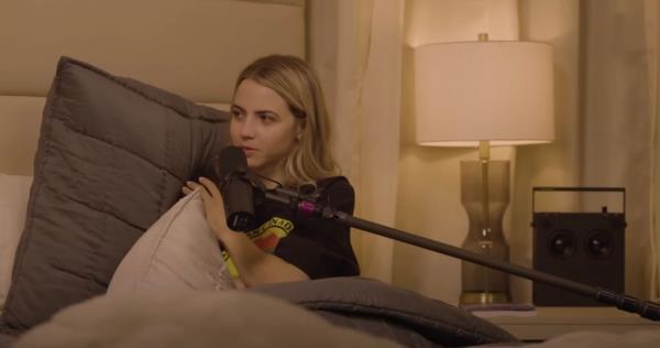 Bobbi Althoff sitting in bed with a microphone.