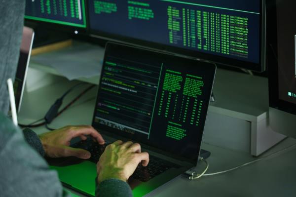 Hacker's hands using laptop computer to code program. 